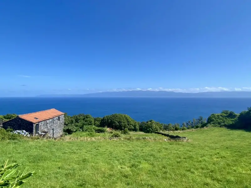 a stone building on a grassy hill with a body of water in the background