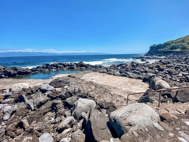 a rocky beach with a metal railing