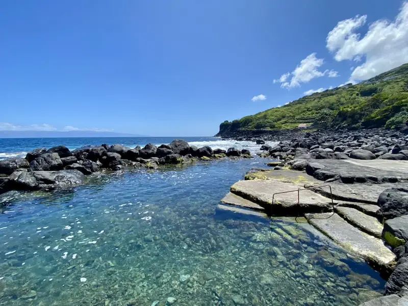 a rocky shore with a body of water and a hill